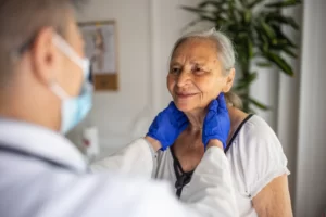doctor is checking the lymph nodes of an elderly woman during consultation