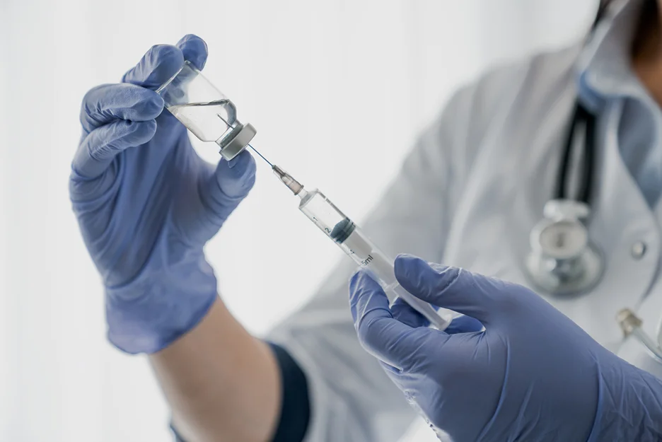 Medical provider holding a syringe and a vial of Covid vaccine