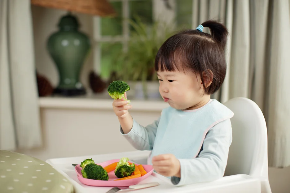a toddler eating vegetables