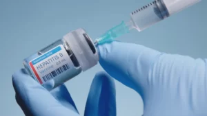 Medical provider holding a syringe and a vial of Hepatitis B vaccine
