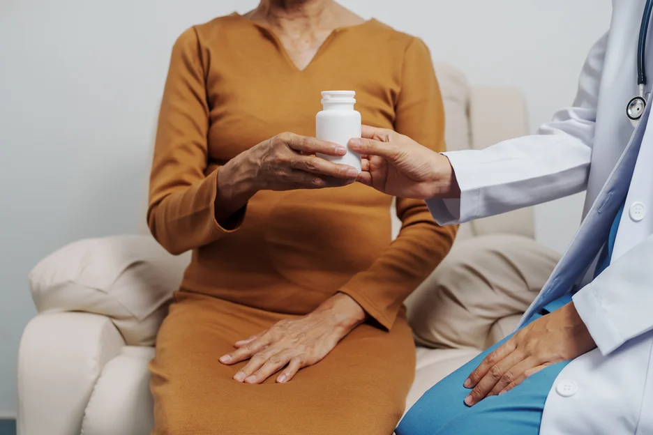 a doctor hands over a pill bottle to the patient