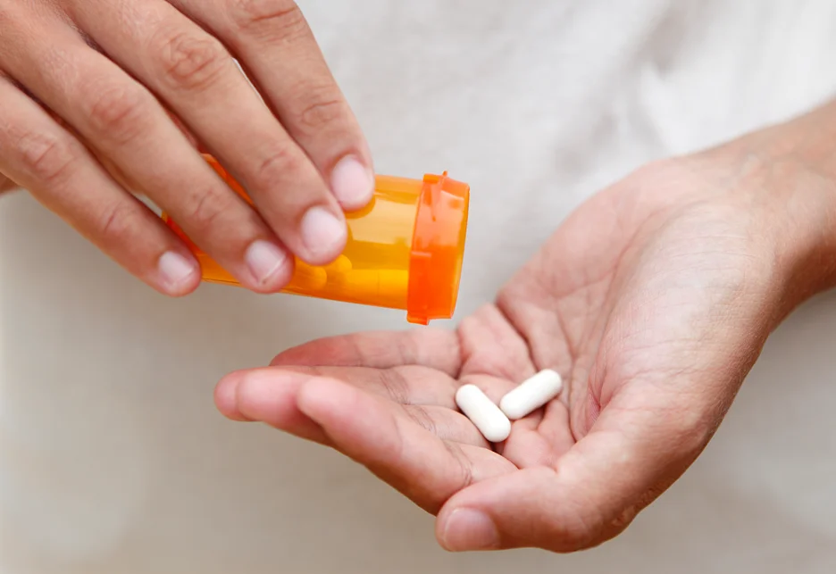 a woman holding two pills and a pill bottle