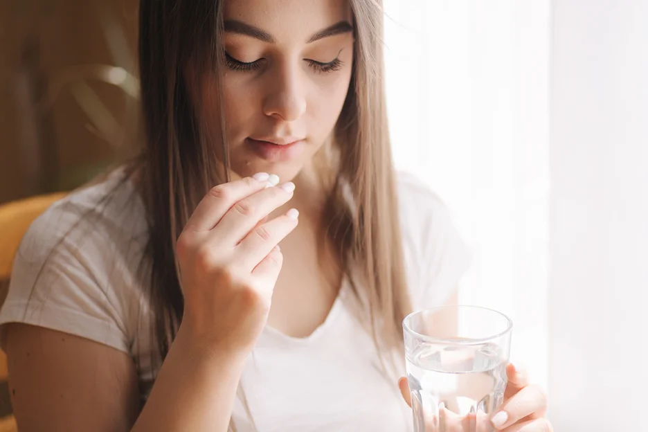 a young woman taking a pill