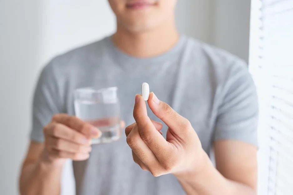 a man holding a pill and a glass of water